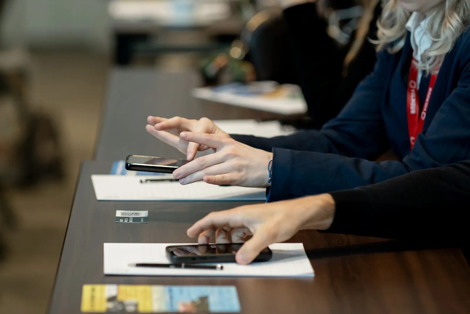Konferencijos dalyviai telefonuose peržiūri renginio nuotraukas