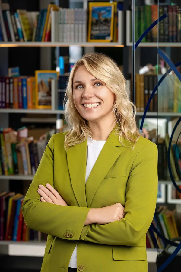 Business portrait of a woman in a green blazer against an office bookcase