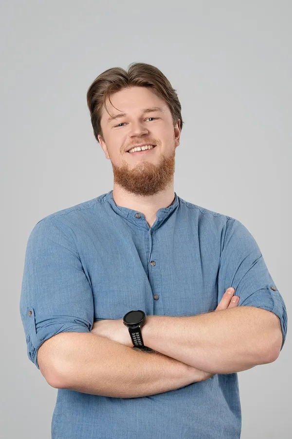 Portrait of a bearded man in a blue shirt on a grey studio background