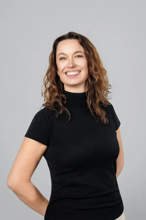 Portrait of a woman with curly hair in a black top on a studio background